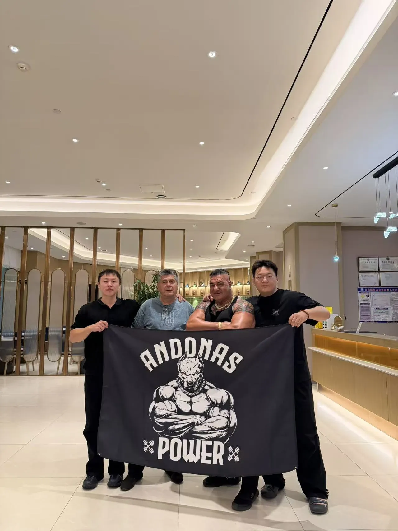 Four visitors and hosts holding a gym-brand banner together